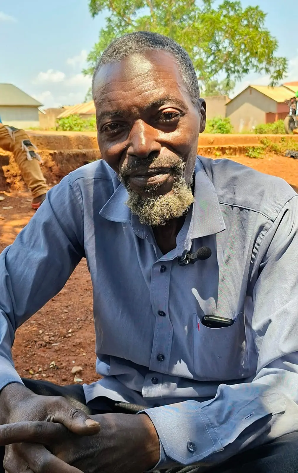 Ndegge, a carpenter in Mawero, Busia, sitting beside his worksite