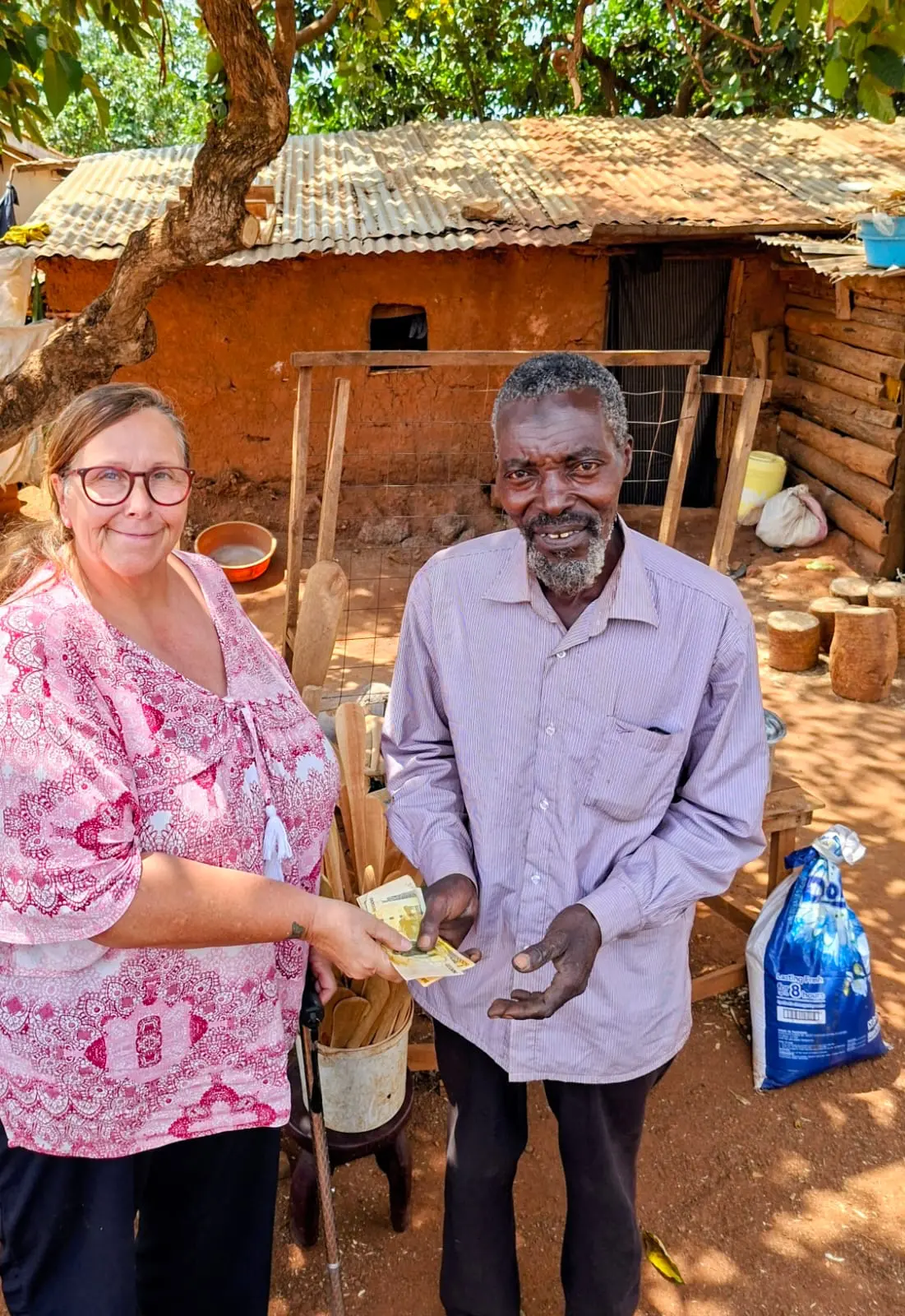 A Burlcore Foundation representative hands Ndegge his funding outside his home in Mawero, Busia