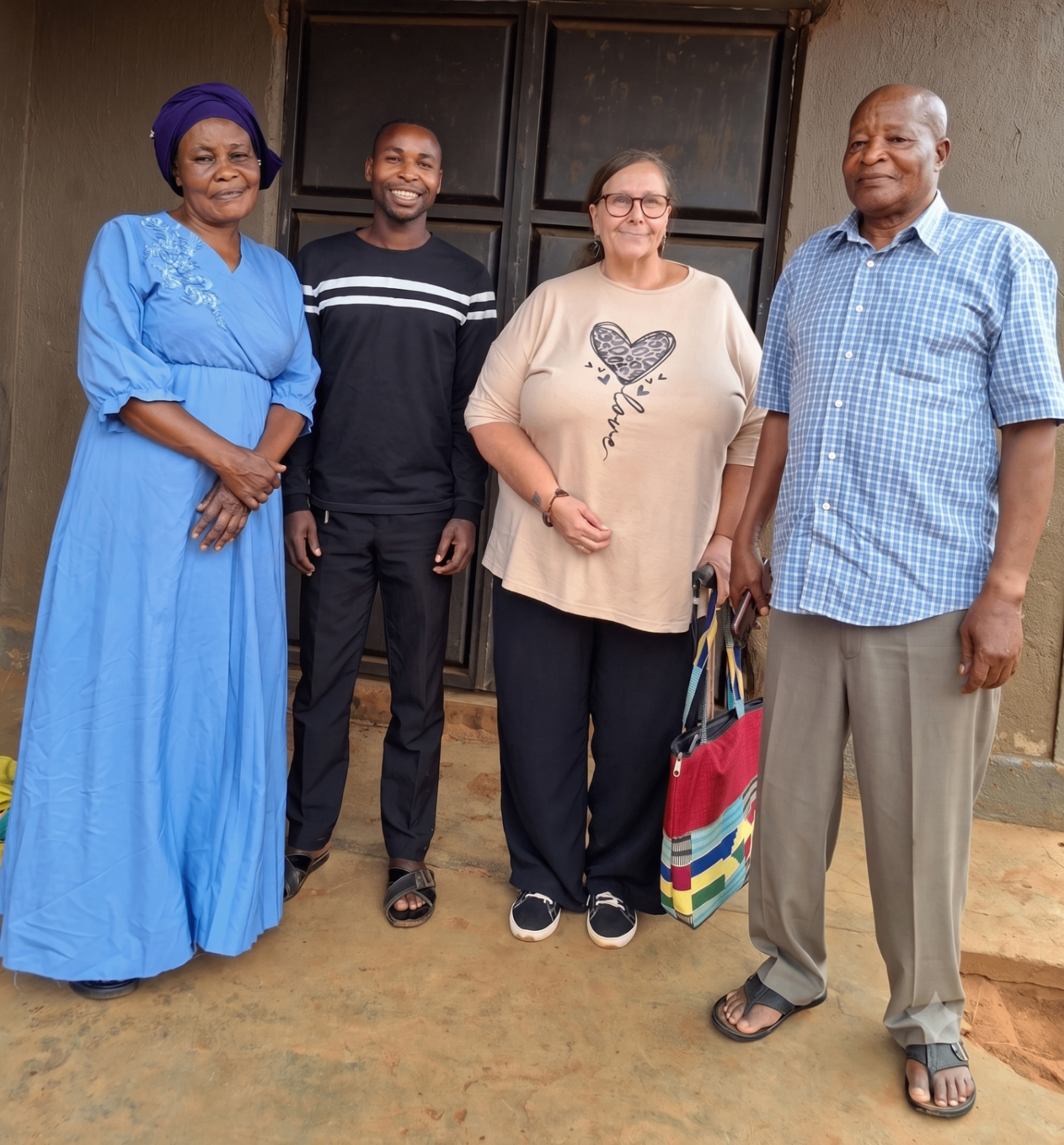 Burlcore Foundation trustees standing with community members outside a home in Busia during a welfare drop-in