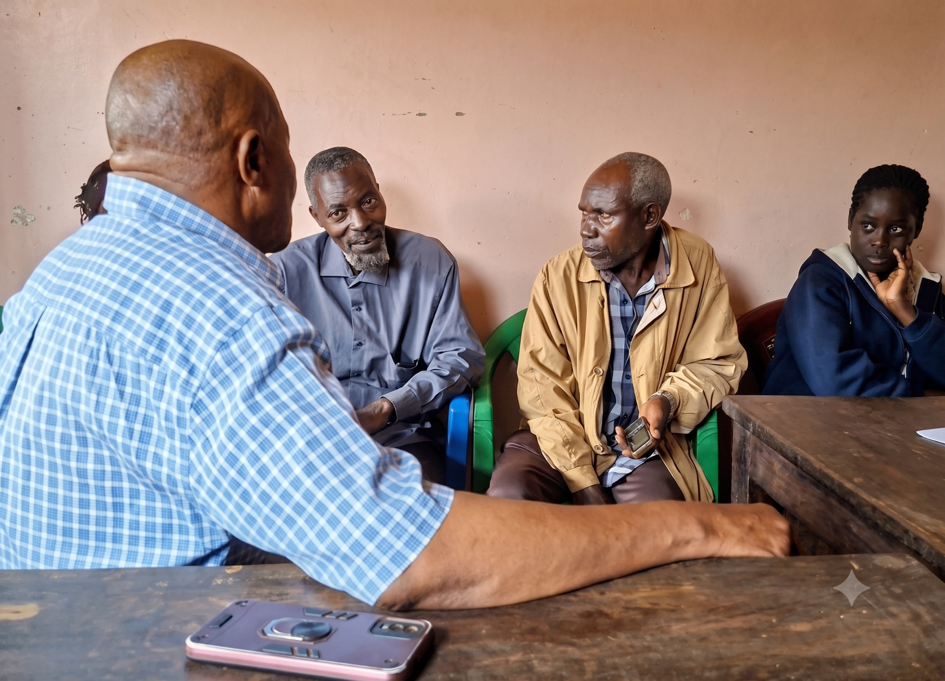 A Burlcore trustee listening to community elders during a weekly welfare drop-in in Busia