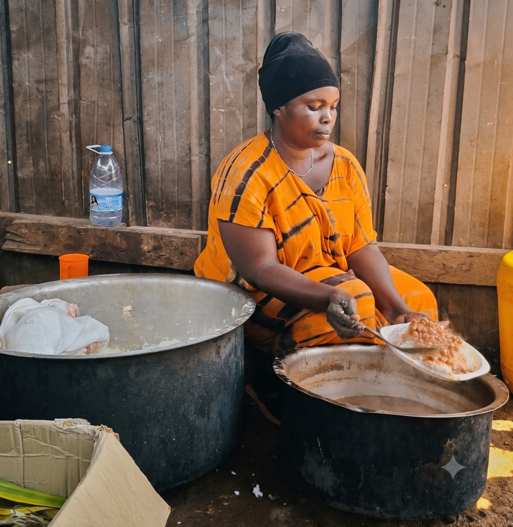 A cook serving rice and beans from large pots for the on-site team