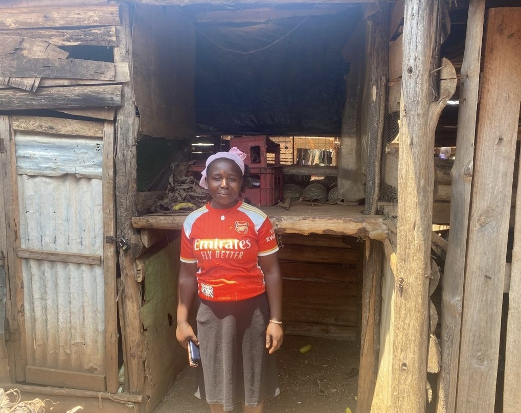 Babra standing at her newly funded market stall in Busia, Uganda