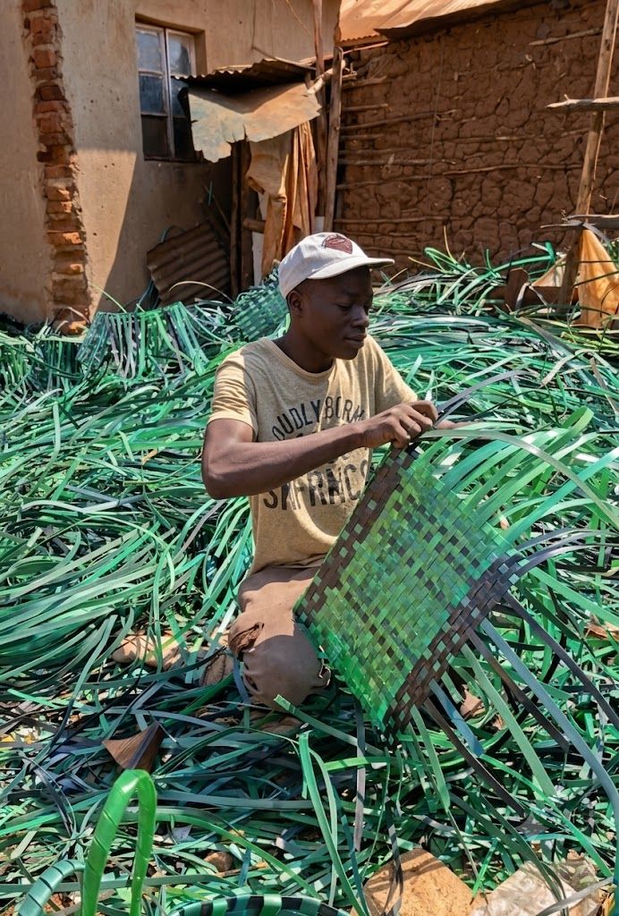 A younger Mawero weaver hand-weaving a green basket