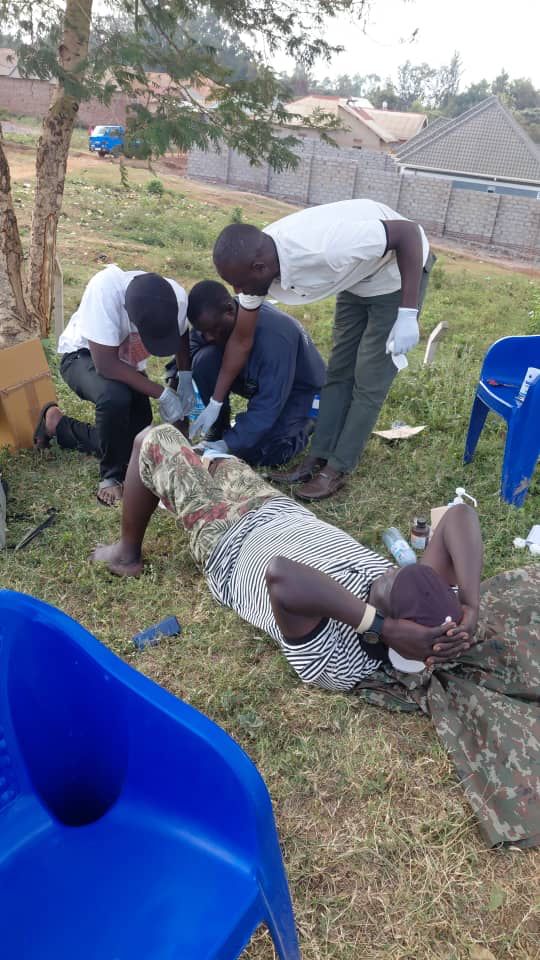 Trainees practising casualty assessment and wound care on a colleague during first aid training in Busia